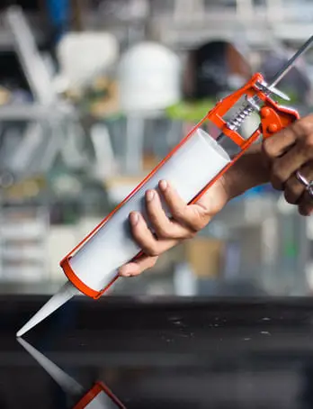 Professional applying adhesive sealant with cartridge gun for construction and industrial bonding applications