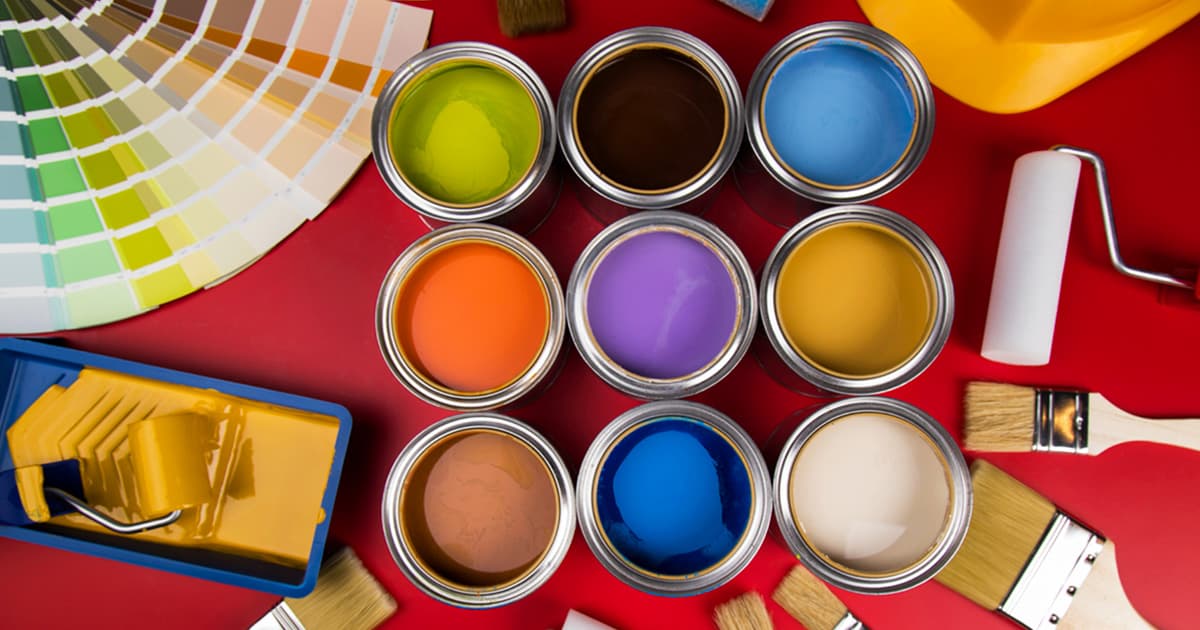 Vibrant paints in cans alongside applicators such as brushes and rollers. This image is related to a blog post titled 
